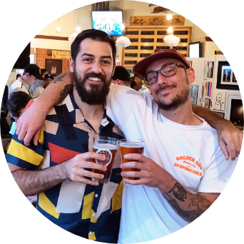 A picture of Side Hustle Art Show owners Adam Raiola and CJ Coccia cheersing a beer from their first group art show in Denver, Colorado